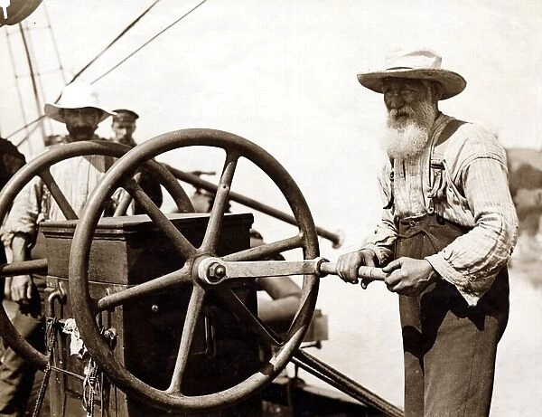 An old man turning the wheel of the diving pump on board the salvage ship Lyons