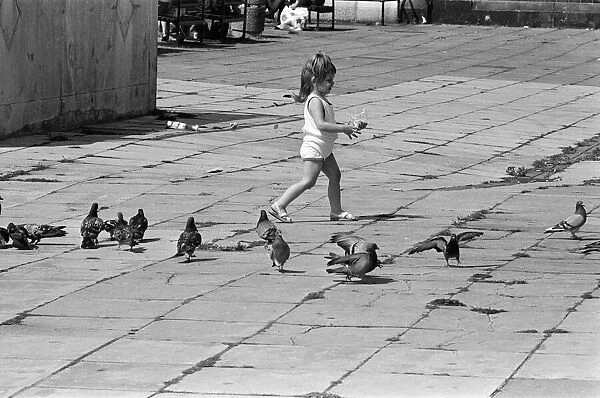 Pier Head, Liverpool, Merseyside, 17th August 1988. Young child plays with pigeons