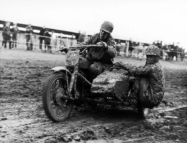 Plastered in mud, two competitors race around the tarck in a side car event at