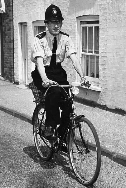 A police officer doing his rounds on a bicycle in Cambridgeshire. July 1964