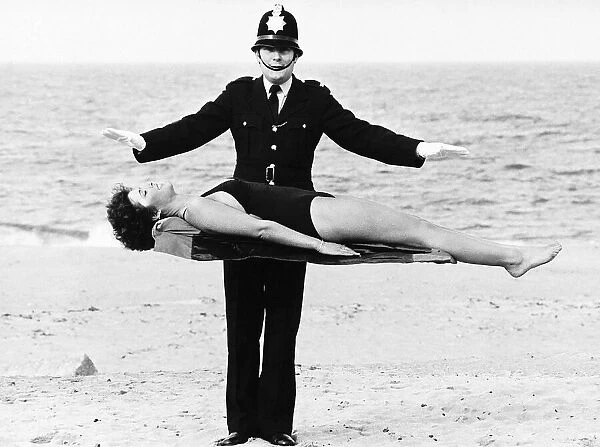 Policeman Bob Averill from Wallsend Tyne and Wear levitates Julia Wall on the sands of