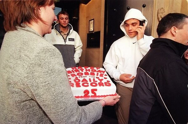 Robbie Williams gets a 25th birthday cake from Margaret Mallon February 1999 as he walks