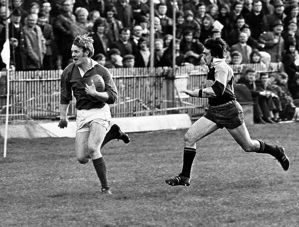 Roy Mathias, Llanelli Rugby Union Player, chased by Keith James of Newport