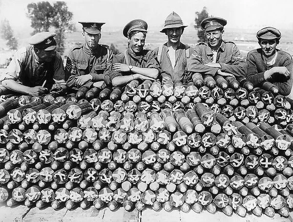 Soldiers from Britain and the Empire leaning of a large pile of 18 pounder shells during