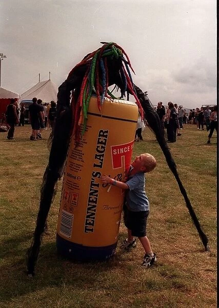 Stilted figure at T in the Park wearing a bright coloured wig standing over an inflatable