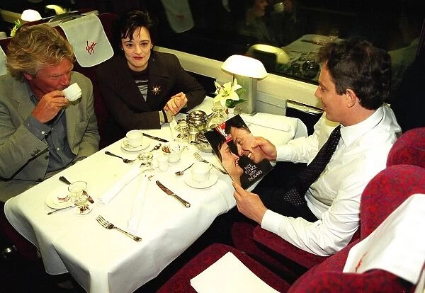 Tony Blair MP reads Yes magazine sitting in dining carriage of train with wife Cherie