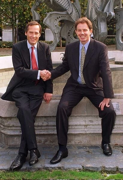 Tony Blair shakes hands with new MP Tony Howarth sitting at a fountain with sculpture in