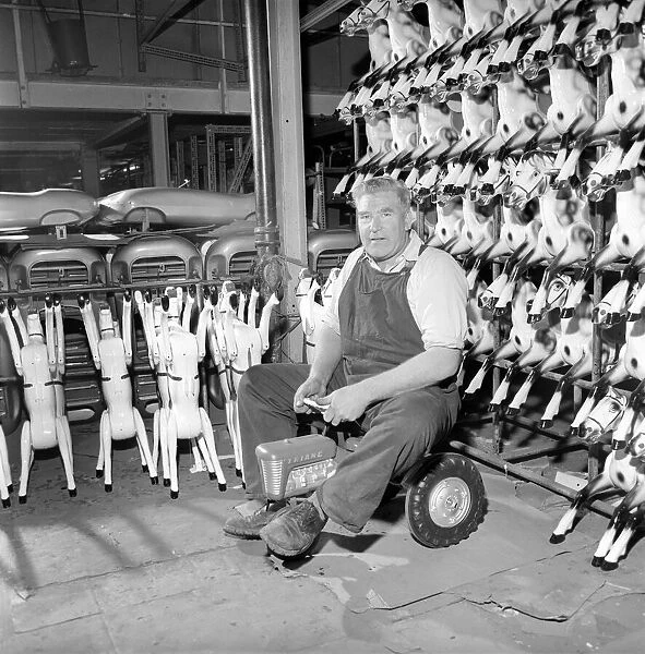 Toy tester: Man sitting on toy tractor at the Tri-ang factory in Merton South London 1965