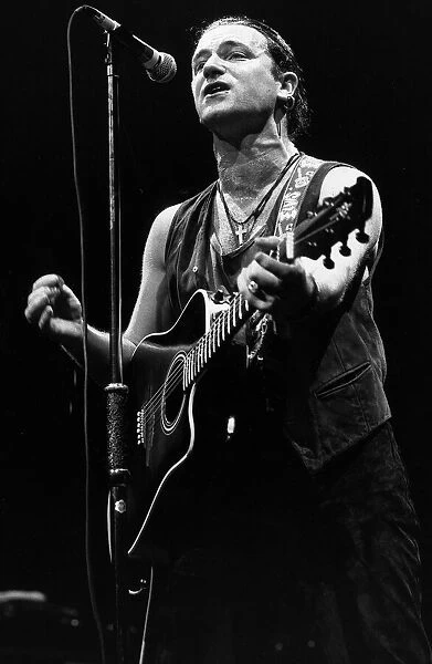 U2 Irish pop singer Bono playing guitar and singing at Wembley Arena in