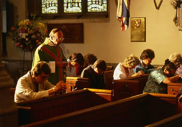 Vicar in church with people praying in Hungerford August 1987