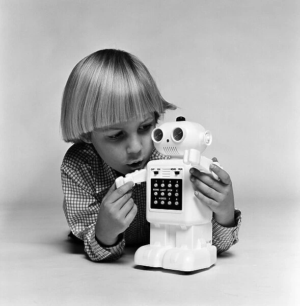 A young boy playing with a Computer48 toy robot. December 1980