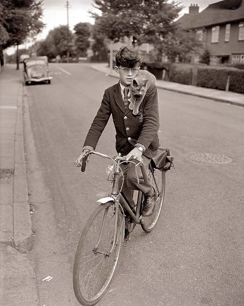 A young schoolboy comes home from school on his bicycle