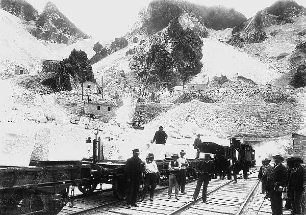 Excavators in front of a railroad convoy loaded with blocks of marble at Ravaccione, in the Apuan Alps