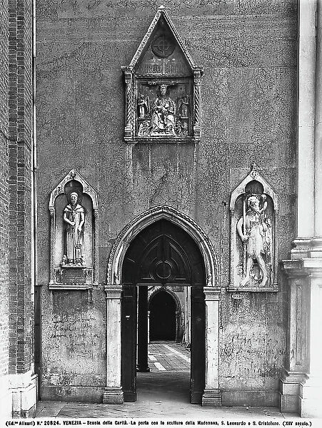 Detail of the faade of the Scuola Grande di Santa Maria della Carit in Venice. There are three marble aedicules above the door, framing the Madonna being worshipped by St. Leonard and St. Christopher