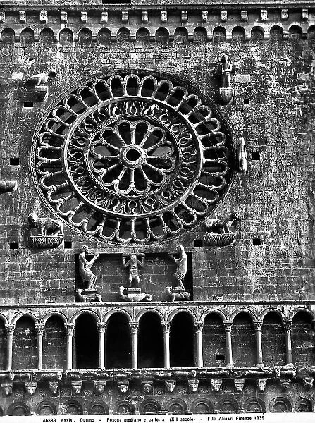 Middlr rose window of the Cathedral of Assisi. At its corners, the symbols of the four evangelists and at the base, three telamons. Under the rose window the hanging gallery and small arches