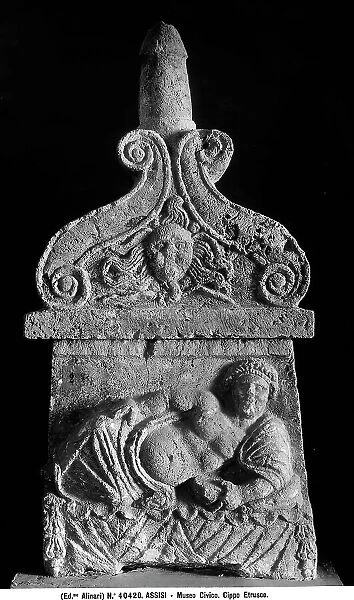 Tombstone decorated with a prone male figure and a spiral sun, work located in the Civic Museum of Assisi
