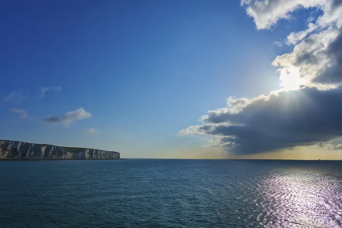Framed Print : Brilliant sunlight through clouds over ocean and cliffs Print