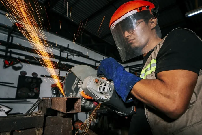 Framed Print : Close-up of a man using a grinder on an anvil Print