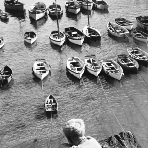 Print of a young boy looking down at tethered boats in Portscatho Harbour Print of a young boy looking down at tethered boats in Portscatho Harbour