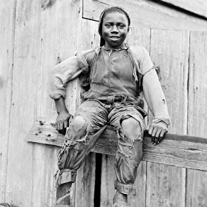 African-American boy sitting on a fence in America