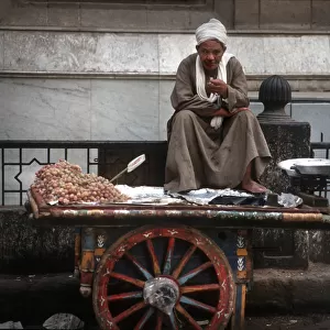 Cairo street seller sits on his barrow smoking a cigarette
