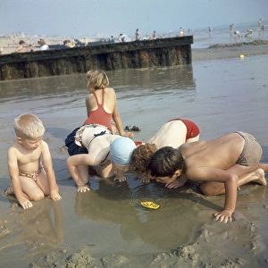 Children playing in a pool on a sandy beach