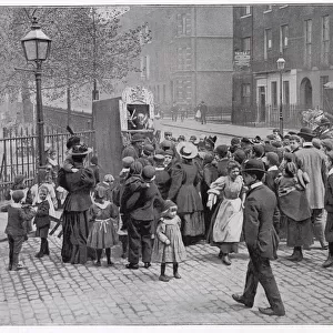A group of amused London children gather round to watch a traditional Punch and Judy