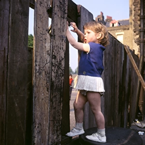 Little girl climbing on a fence, Balham, SW London
