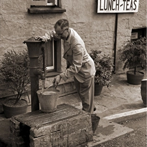 Man filling a bucket at a water pump