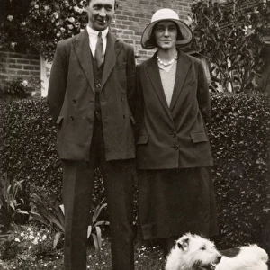 Man and woman with a terrier dog in a garden