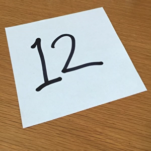 Piece of paper on a desk with a large number 12