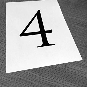 Piece of paper on a desk with a large number 4
