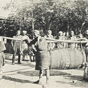 Porters carrying a large barrel on two long yolks