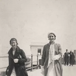 Two women stroll along the seafront