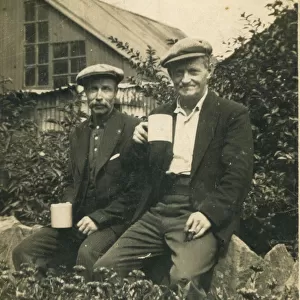 Two working class men enjoying a break from work with a cup of tea. Date: 1920s