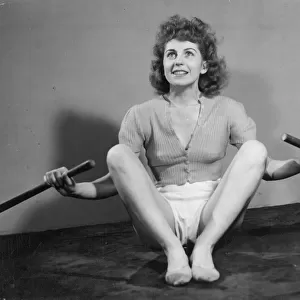 A young woman exercising with a pair of oars. Date: 1940s