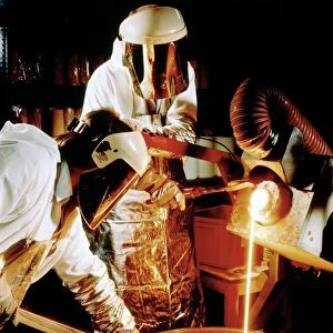 Foundry workers pouring molten metal into an ingot