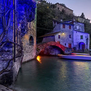 Boat in motion under the illuminated Nesso bridge, Lake Como, Lombardy, Italian Lakes