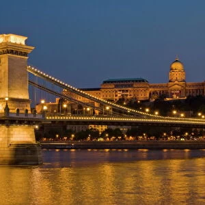The Chain Bridge (Szechenyi Lanchid), over the River Danube, illuminated at sunset with the Hungarian National Gallery also lit, behind, Budapest