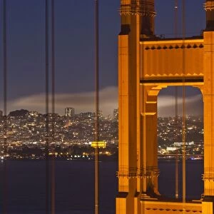 Closeup view of the north tower of the Golden Gate Bridge at sunset with the San Francisco city skyline, San Francisco, California, United States of America