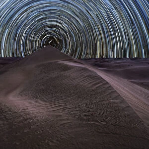Concentric circumpolar star trail above sand dunes in the Rub al Khali desert, Oman