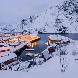 Dusk lights on the fishing village surrounded by snowy peaks, Nusfjord, Nordland