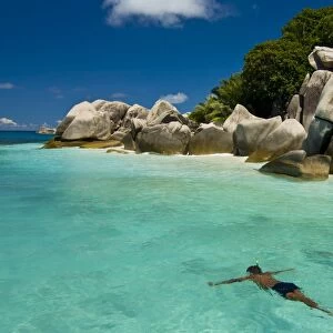 Local man swimming at the Granite rocks at Ile aux Cocos, Seychelles, Indian Ocean