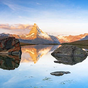 Matterhorn lit by sunrise reflected in the calm water of lake Stellisee, Zermatt