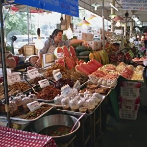A shopkeeper pointing at fruit on one of the food stalls