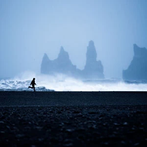 Tourist running on Black Sand Beach, Iceland, Polar Regions