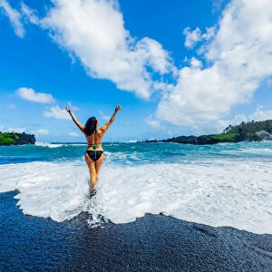 Woman enjoying the sun on one of Mauis black sand beaches, Maui, Hawaii