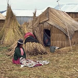 A woman with her sewing sitting outside her reed house
