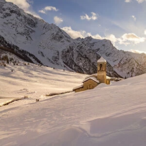 Alpine church of San Bernardo at sunset light in a mountain valley during winter season