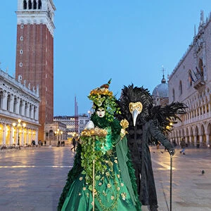 A couple wearing masks and Venetian costume stand in St Marks square during the